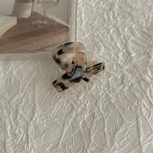 Detail of tortoise shell acetate hair claw clip with gold Babyvovo branding on white fabric