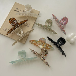 Set of eight large acetate hair claws in various marble colors on a warm cream background