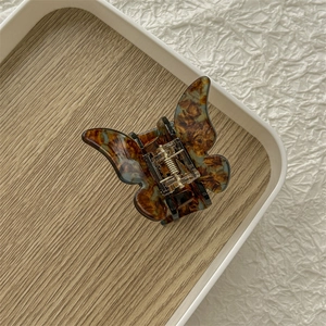 Gros plan sur pince à cheveux papillon en acétate avec motif écaille sur plateau