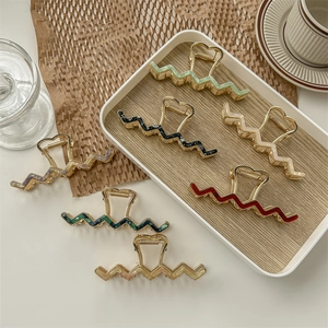Elegant wavy claw clips with heart handles in assorted colors on a marble tray