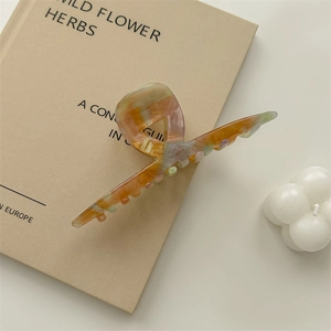 Detailed macro of large acetate claw clip with colorful marble pattern on vintage book