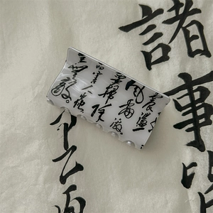 Detail of a minimalist hair claw clip with black ink calligraphy on a translucent gray base