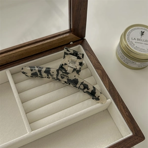 Detailed macro view of acetate hair claw with marble texture and silver metal spring