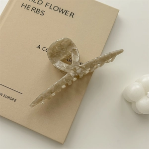 Detailed macro view of large acetate claw clip with cream marble texture on a book