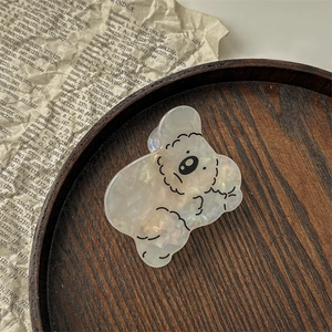 Détail d'une pince à cheveux koala en acétate nacré avec des paillettes brillantes