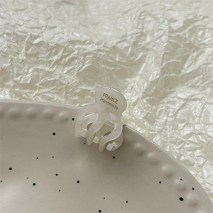 Détail d'une mini pince à cheveux en acétate blanc crème avec texte France Handmade