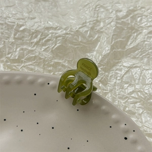 Détail d'une mini pince à cheveux vert foncé sur assiette avec marquage fait main