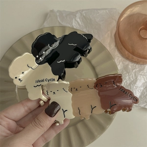 Pinces à cheveux mignonnes en forme de chiot en noir, crème et marron sur une assiette