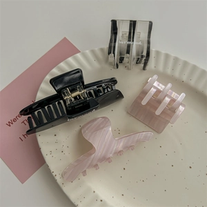 Set di quattro eleganti mollette per capelli marmorizzate e nere su un piatto decorativo