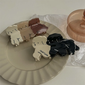 Pinces à cheveux mignonnes en forme de chiot en crème, marron et noir sur plateau décoratif