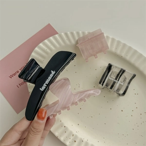 Set di quattro eleganti mollette per capelli nere e marmorizzate in un piatto decorativo