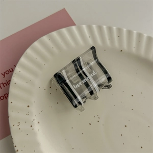 Vista dettagliata di un fermaglio per capelli a righe bianche e nere su un vassoio ceramico