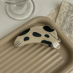 Détail d'une pince à cheveux motif dalmatien posée sur un plateau beige épuré