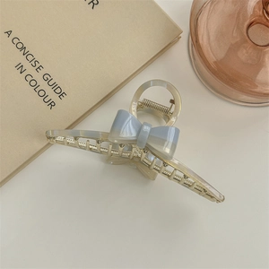 Details der Haarklammer mit blauer Schleife aus Acetat und goldener Metallfeder