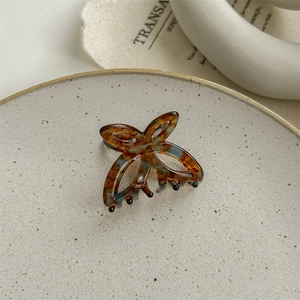 Détail artistique d'une pince à cheveux papillon en acétate avec texture marbrée