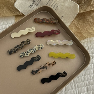 Set of 10 vintage geometric acetate hair clips in diverse patterns on a gold tray