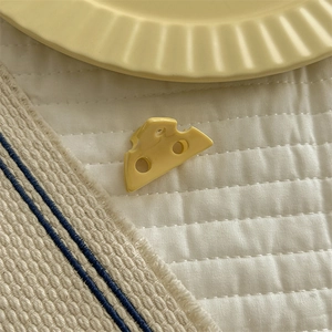 Close-up of yellow cheese shaped hair claw clip on a decorative ceramic plate
