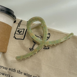 Vue détaillée d'une pince à cheveux à fleurs vert olive avec ressort argenté sur un sac
