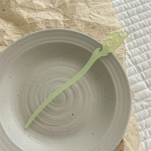 Gros plan d'une épingle à cheveux vintage vert pâle avec des motifs de nuages