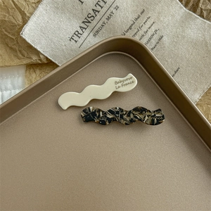 Close-up of wavy acetate hair clips in cream and tortoiseshell on a vintage tray