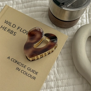 Close-up of tortoise shell pattern acetate hair claw clip with golden metal base on a book