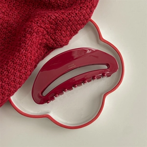 Detail of red acetate hair claw clip with golden France Handmade text on ceramic plate