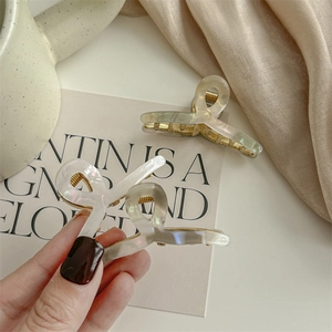 Elegant pearlescent hair claw clips set for women with golden metal teeth and satin background