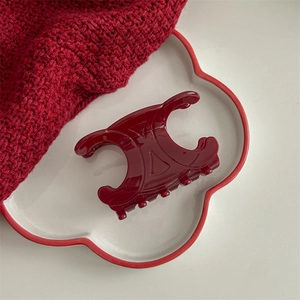Detailed macro view of the dark red acetate Triomphe shape hair claw clip on a plate