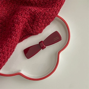 Detail of a deep red acetate bow hair claw clip with golden France Handmade text