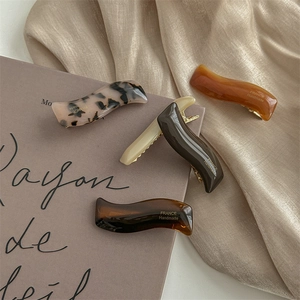 Lot de quatre barrettes à cheveux en acétate écaille et ambre sur fond de satin