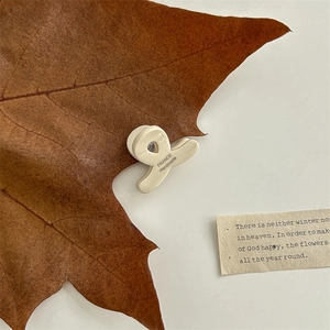 Close-up of cream acetate hair claw clip with cross twist design on autumn background