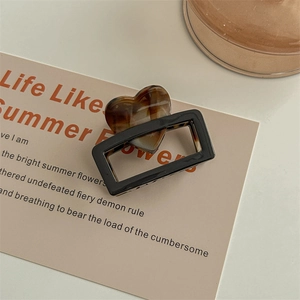 Detail view of square hair claw clip with heart-shaped tortoiseshell pattern and black frame