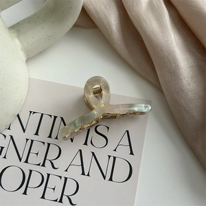 Detail of elegant champagne pearlescent hair claw clip with golden metal spring
