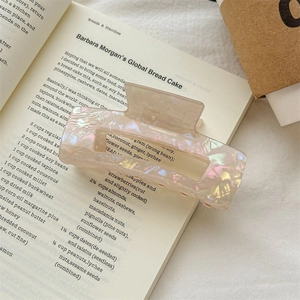 Detail shot of the pearlescent marble hair claw clip on an aesthetic book background