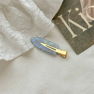 Detail of blue iridescent acetate hair clip with golden alloy duckbill clip and sawtooth edge