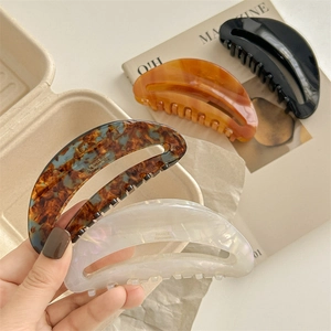 Large acetate hair claws in black, amber, and pearl white colors for long hair