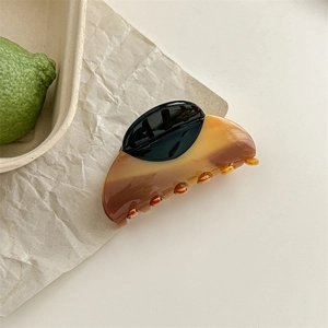 Retro amber wood grain cellulose acetate hair claw clip on a minimal wooden tray