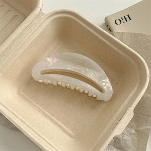 Macro shot of half-moon acetate hair claw with iridescent white mother of pearl finish