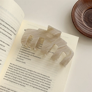 Detailed macro view of large marble-pattern acetate hair claw on a decorative book