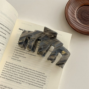 Macro detail of high-end acetic acid hair claw with marble pattern on vintage book