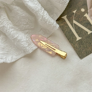 Detail of pink marble textured acetate hair clip with golden metal alligator clamp