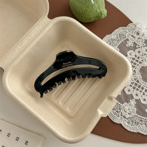 Close-up of black acetate hair claw clip with gold Barrette La France text engraving