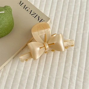 Detailed macro view of cream beige bow claw clip with France Handmade lettering