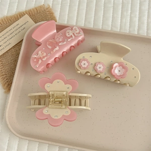 Elegant acetate flower hair claws with rhinestones in a soft pink decorative tray