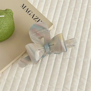 Macro detail of bow-shaped acetate hair claw with pastel marble texture and France engraving