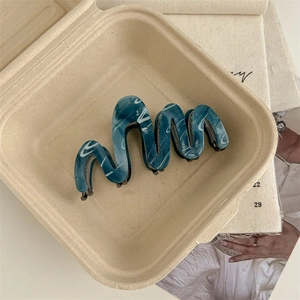 Detaillierte Draufsicht auf eine marmorierte blaue Haarklammer aus Acetat in einer Box