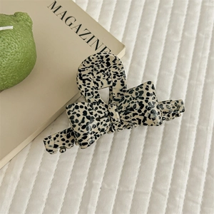 Close-up of handmade acetate bow hair claw clip with black and white spotted pattern