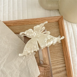 Detail of cream butterfly hair claw clip with gold lettering on pearlescent acetate finish