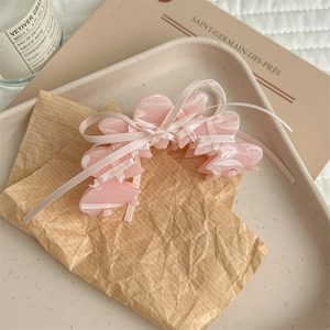 Vue détaillée de la pince à cheveux en acétate rose avec un nœud papillon en ruban satin