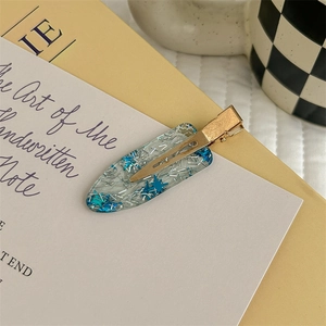Dettaglio di un fermaglio in resina con paillette a stella blu su carta decorativa